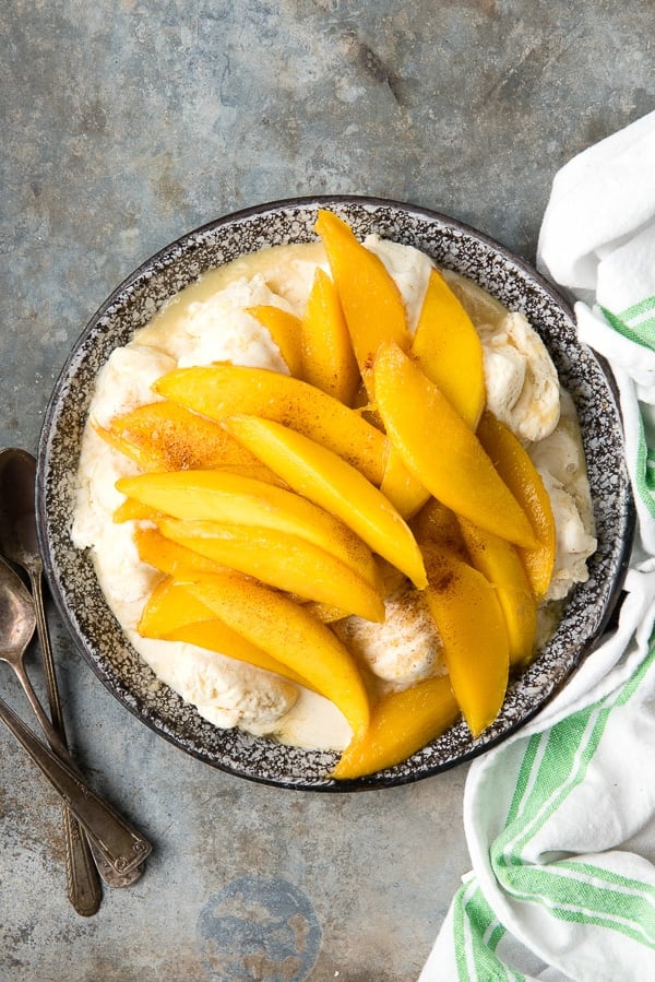 flambéed mangoes served over vanilla ice cream, served in a silver bowl