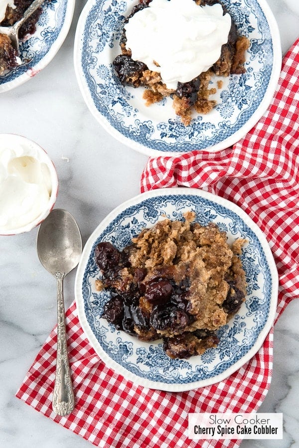 2 plates of Slow Cooker Cherry Spice Cake Cobbler, one topped with whipped cream