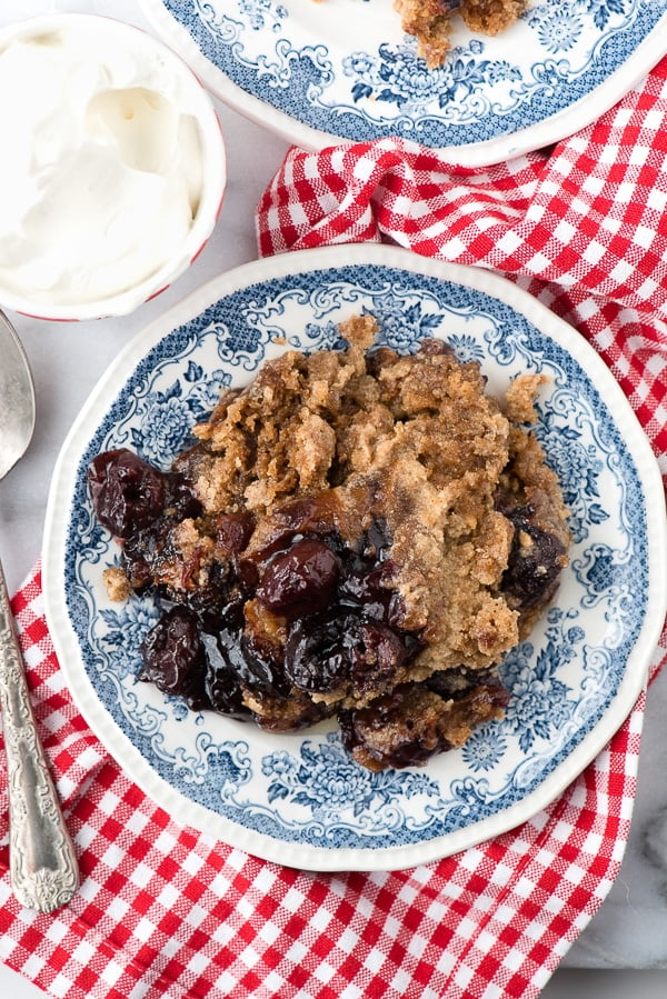 bowl of Slow Cooker Cherry Spice Cake Cobbler on a red and white gingham napkin