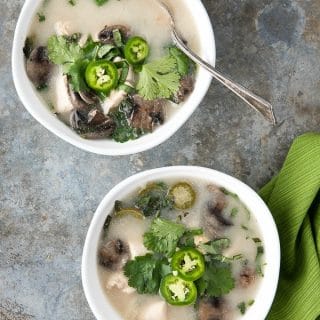 titled photo - 2 bowls of Slow Cooker Thai Chicken Mushroom Coconut Soup on a granite background.