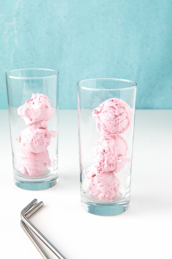 two tall glasses with 3 scoops of strawberry ice cream for making strawberries and cream floats