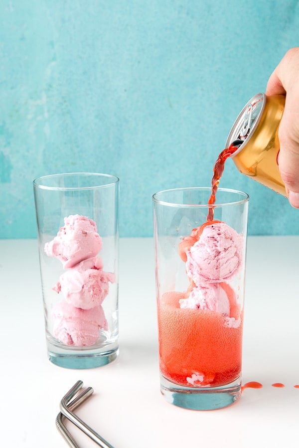 adding strawberry soda to tall glasses to make Strawberries and Cream Ice Cream Floats
