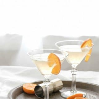 Two The White Lady Cocktails in martini glasses with orange slices on an antique bronze tray