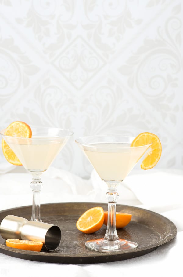 The White Lady Cocktail in cocktail glasses with orange slices and cocktail jigger on bronze tray