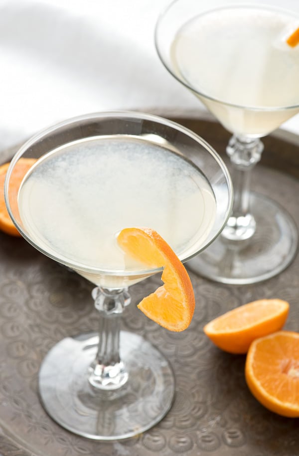 Close-up of The White Lady Cocktail in a martini glass with orange slice on an anitque tray