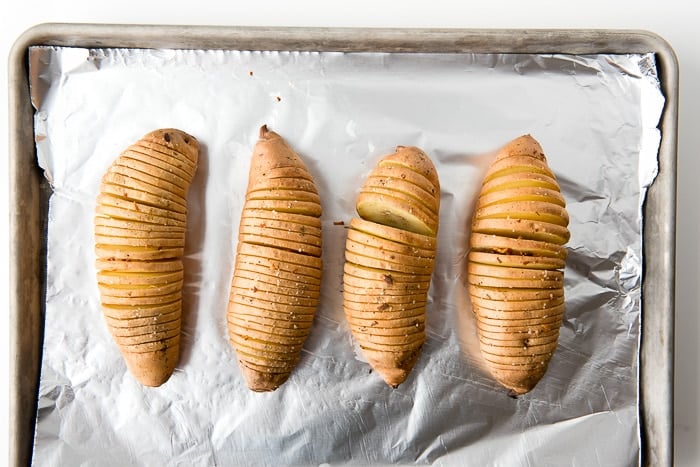 aluminum foil lined baking sheet holds 4 unbaked Hasselback style Sweet Potatoes