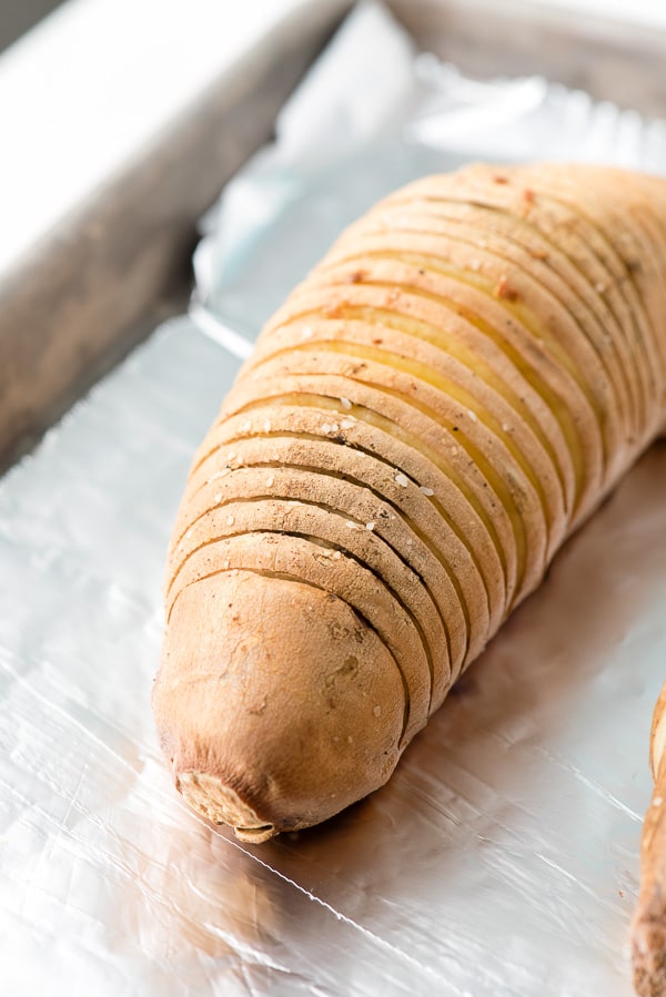 Hasselback style Sweet Potato on a baking sheet, ready for baking