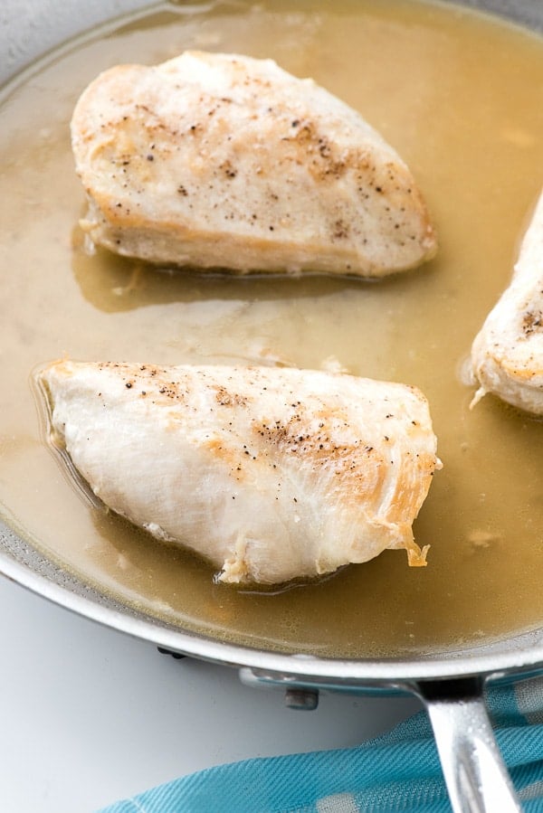 moist bonless chicken breasts cooking in a large aluminum skillet