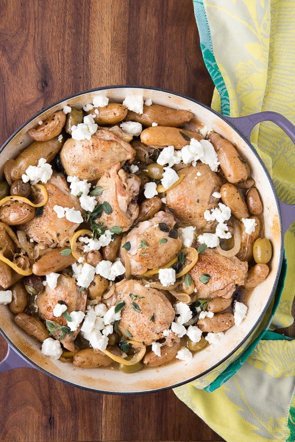 A lavender colored Dutch oven filled with Lemony Greek Chicken Thighs and feta cheese