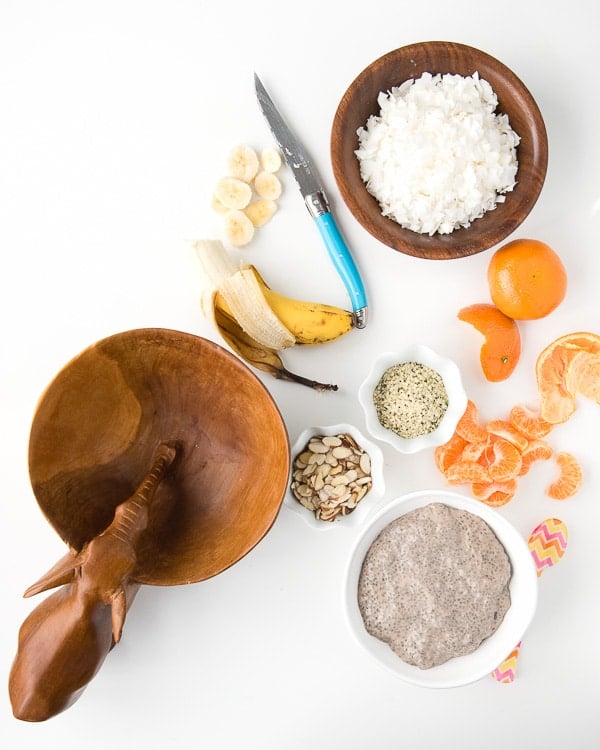 an empty wooden carved bowl and ingredients to make a Roasted Banana Chia Pudding Breakfast Bowl 