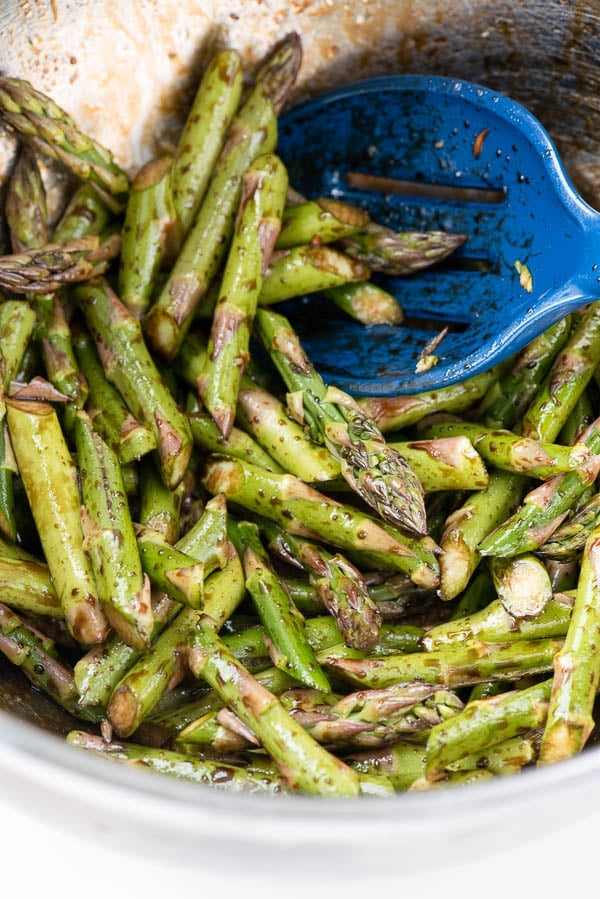 bowl of Balsamic Roasted Asparagus Spears with a royal blue serving spoon