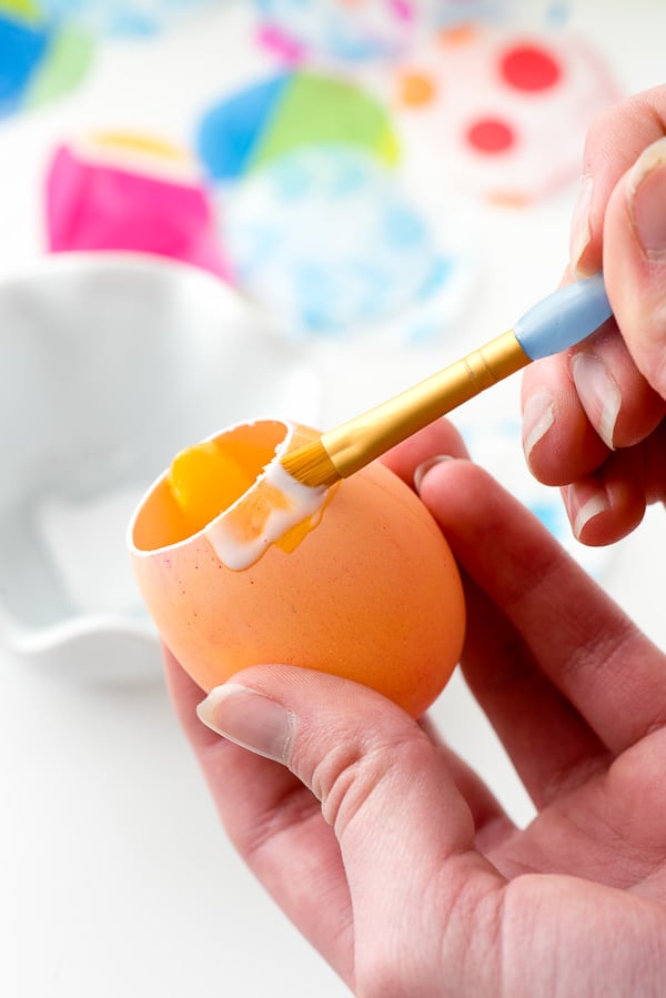 painting white glue around the outside of a confetti egg before adding tissue paper