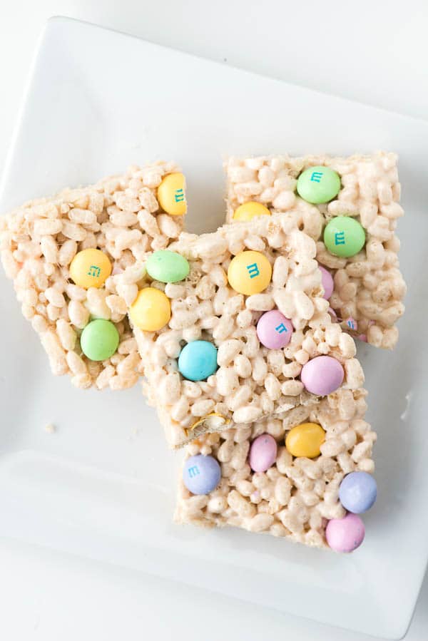 4 squares of Fruity Springtime Crispy Rice Cereal Treats on a white platter