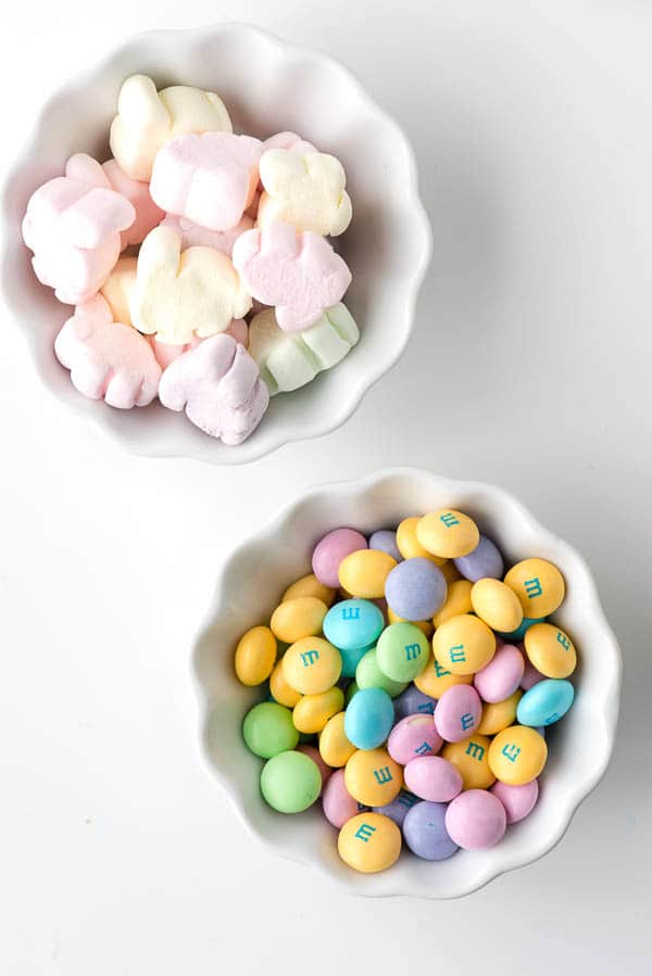 small white prep cups filled with pastel colored mini marshmallows and pastel colored M&amp;M chocolate candies