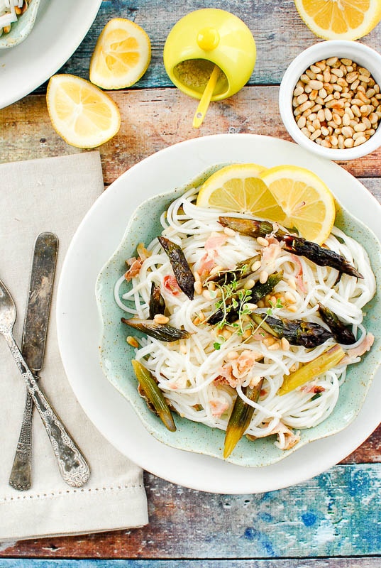 mint green bowl of Lemony Purple Asparagus Pancetta Pasta surrounded by utensils and ingredients to make it