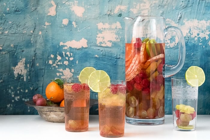 party table setting with a tall pitcher of moscato wine sangria surrounded by individual glasses of the wine sangria