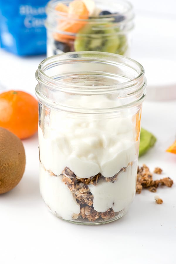 mason jar with layers of yogurt and gluten free granola to make a breakfast parfait