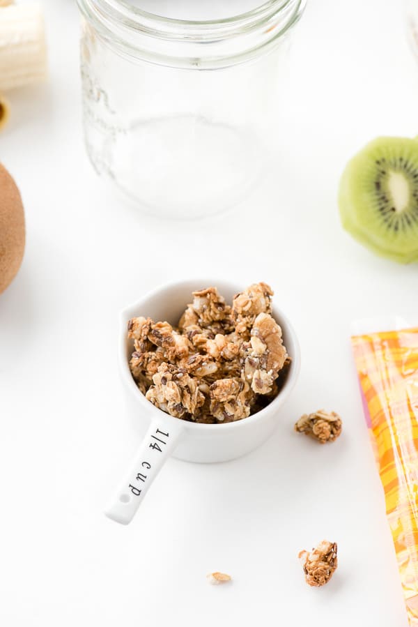 measuring cup of gluten free granola and an empty mason jar to make a breakfast on the go parfait