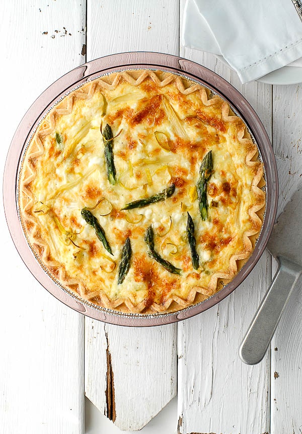 pie dish with Asparagus Leek Romenesco Quiche on a weathered white wooden background