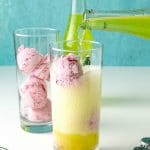 pouring lime soda into a fountain glass filled with strawberry ice cream to make strawberry lime ice cream floats