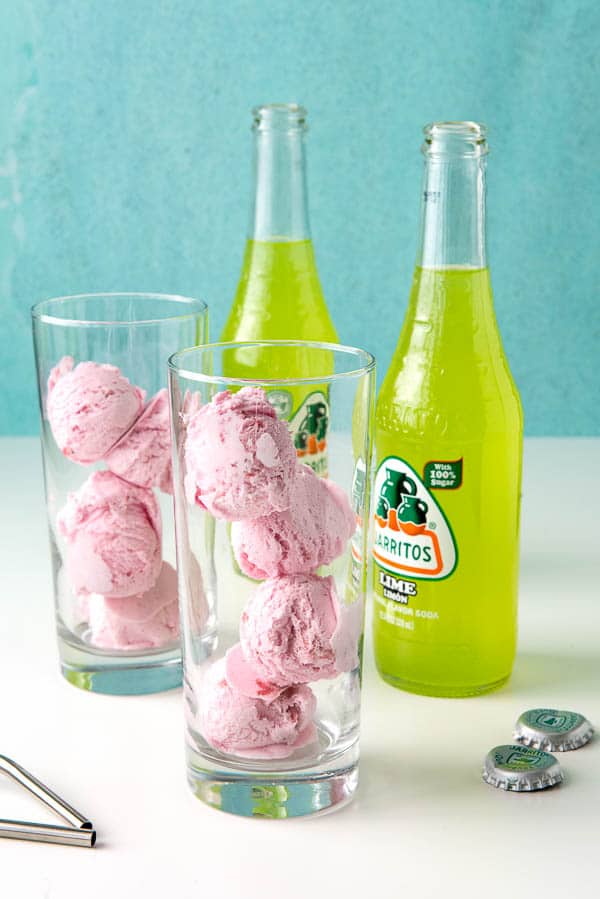 2 fountain glasses filled with 4 scoops of strawberry ice cream sit next to 2 bottles of Jarritos lime soda