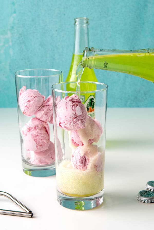 Assembling Strawberry Ice Cream Lime Soda Floats by pouring lime soda over strawberry ice cream