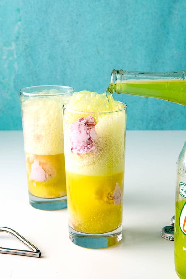 pouring lime soda into a glass with strawberry ice cream to make ice cream floats