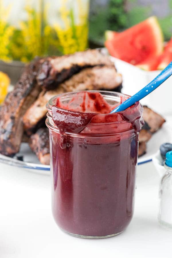 Homemade Blueberry Whiskey Barbecue Sauce in a glass jar with spoon