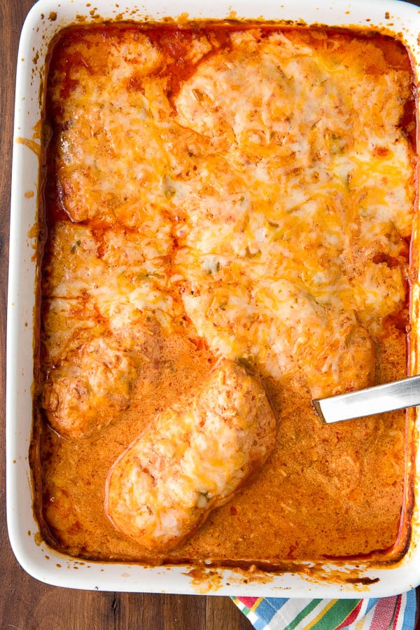 white casserole dish filled with gluten free enchiladas in sour cream sauce stuffed with chicken and green chiles