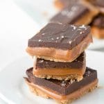 stack of three gluten-free millionaire bars on a white dessert plate