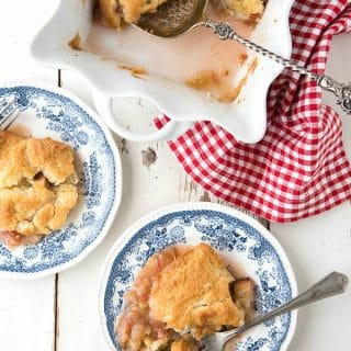 Rhubarb Grunt, a sweet Americana rhubarb dessert with a golden baked top, in a white baking pan with individual servings on plates