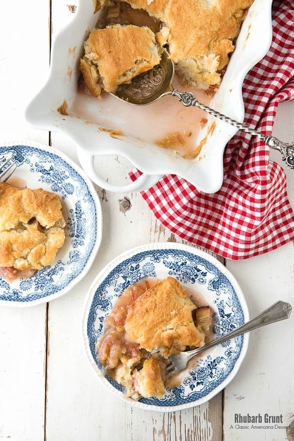 Rhubarb Grunt, a sweet Americana rhubarb dessert with a golden baked top, in a white baking pan with individual servings on plates