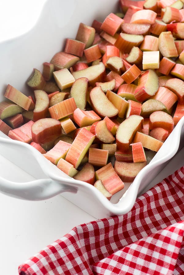 White ruffled baking dish full of sliced fresh rhubarb