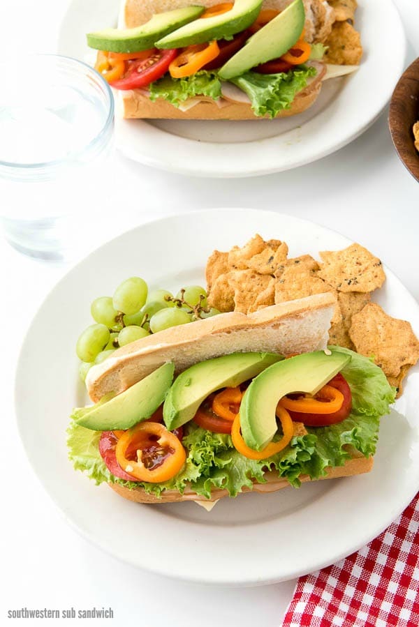 2 plates with Southwestern Sub Sandwiches full of chipotle mayonnaise, turkey, fresh vegetables, and pepper jack cheese.