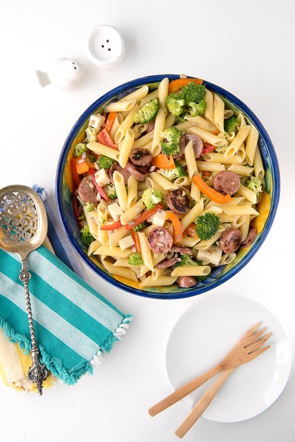 overhead image of a bowl of pasta salad with broccoli, chicken apple sausage slices, penne pasta, and mozzarella cheese cubes