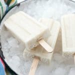 overhead image of boozy banana popsicles lying on a bucket of crushed ice