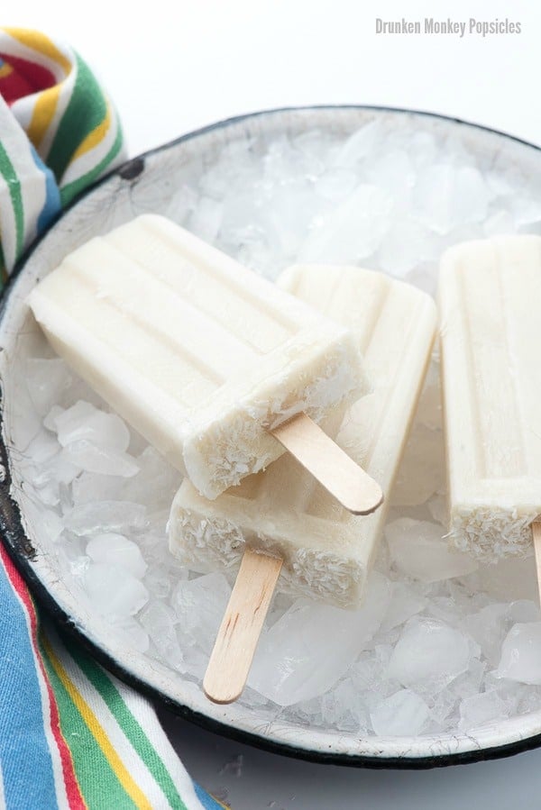 overhead image of boozy banana popsicles lying on a bucket of crushed ice