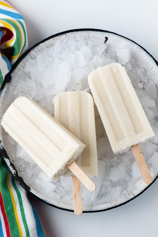 overhead image of boozy banana popsicles lying on a bucket of crushed ice