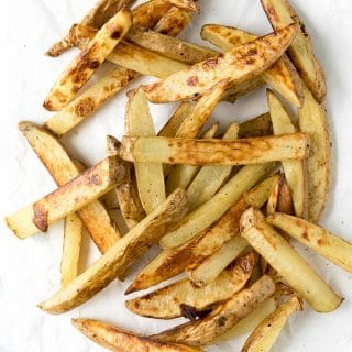 crispy homemade oven fries scattered on white parchment paper
