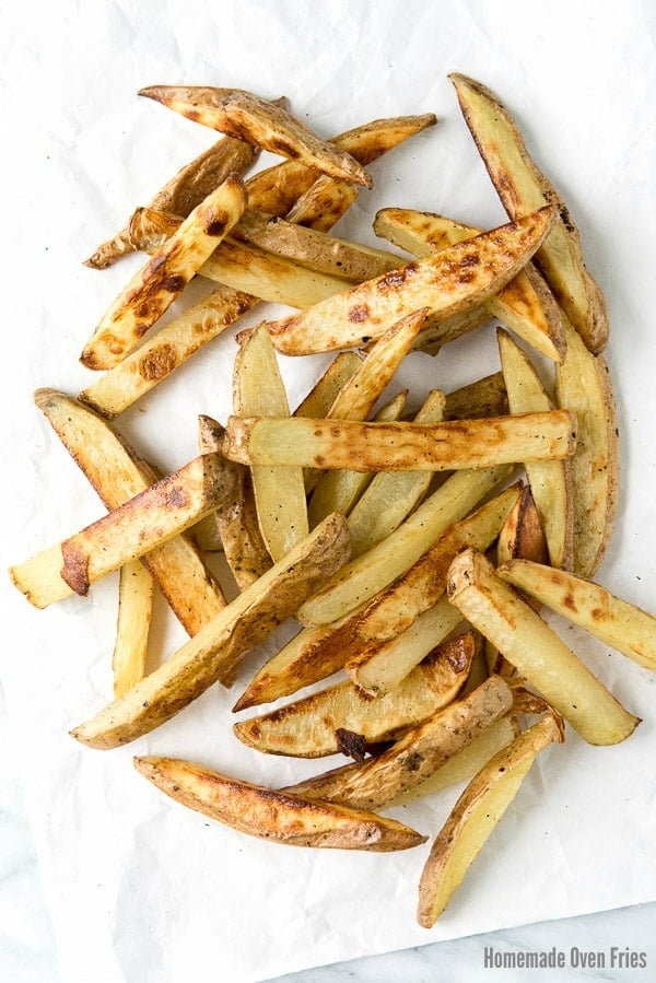 crispy homemade oven fries scattered on white parchment paper