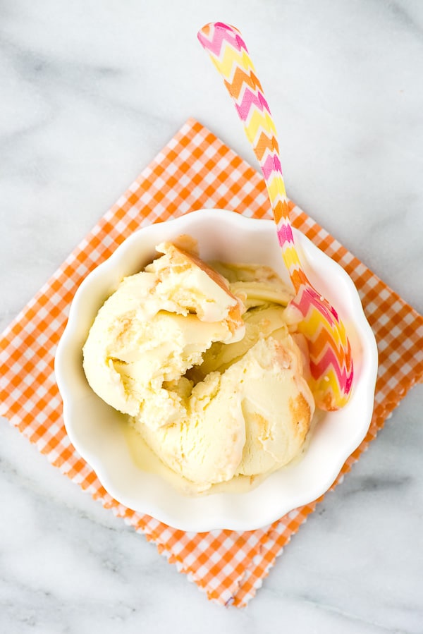 overhead image of a white bowl filled with Olive Oil Peach Ice Cream and a colorful ice cream spoon