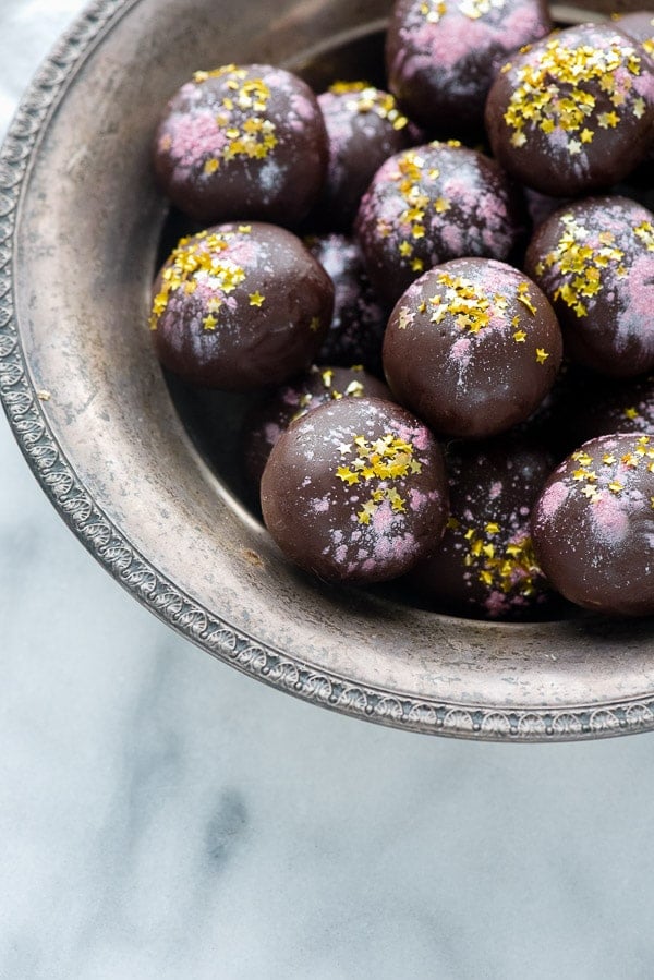 silver bowl full of Rose-flavored Dark Chocolate Truffles garnished with edible gold stars and pink pearl dust