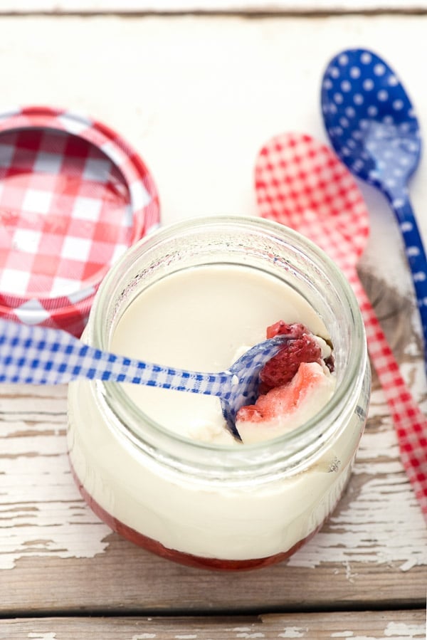 spoon dipping into a jar filled with strawberry panna cotta