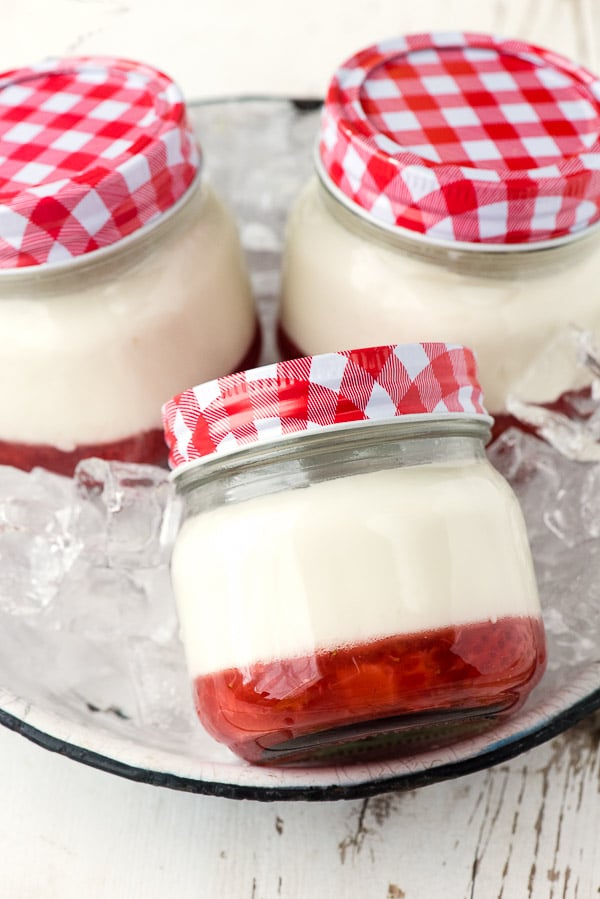 3 servings of Strawberry Jam Panna Cotta prepared in canning jars sitting in a serving tray filled with ice