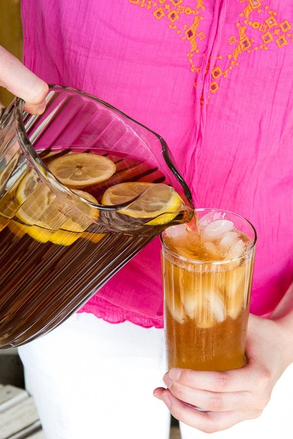 pouring iced tea from a pitcher into a glass