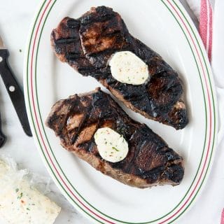herb compound butter on grilled NY strip steaks