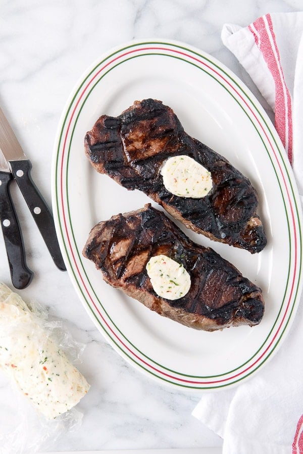 2 New York Strip steaks topped with pats of herbed compound butter