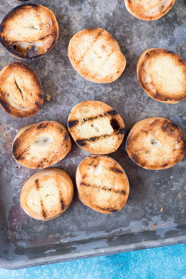 Grilled baguette slices on a baking sheet