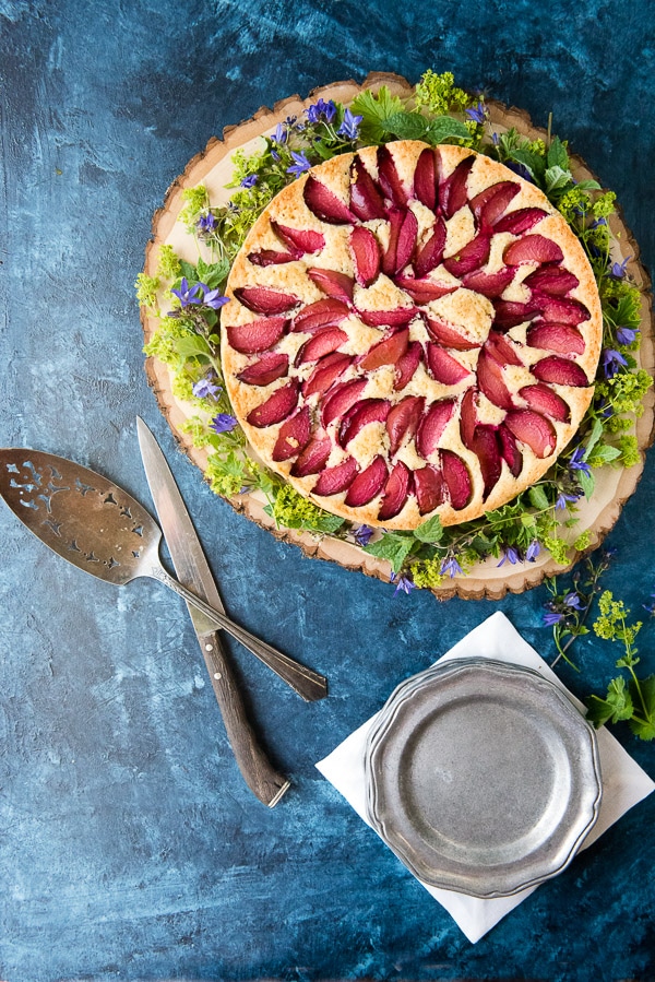 Rustic Plum Cake with violets on a wood slab