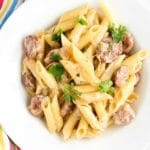 Bowl of Cheesy Sausage Pasta with shallot cream sauce and striped napkin